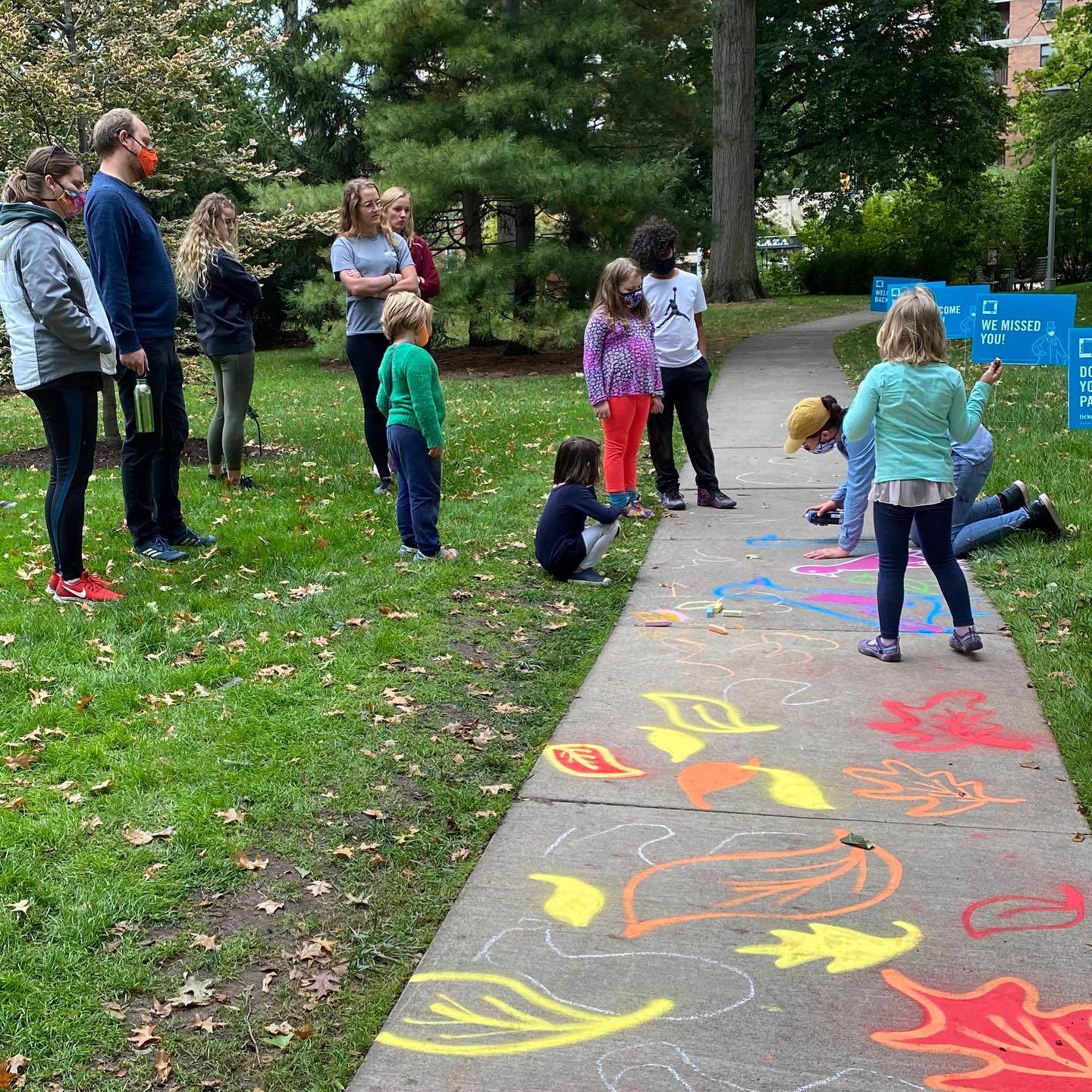 Children and adults join Caroline Jardine on her TMA sidewalk art project.